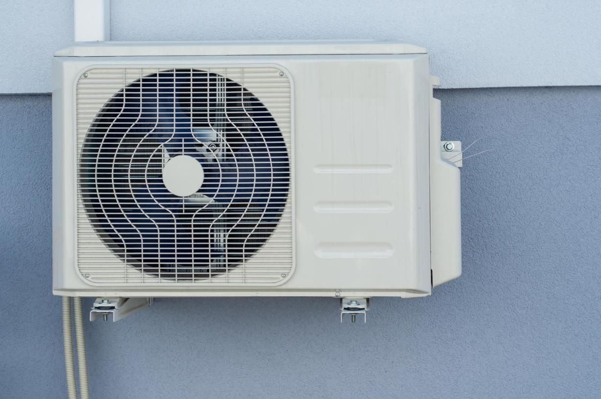A White Air Conditioner is Mounted on the Side of a Building — Enterprise Air That's Cool in Avenell Heights, QLD