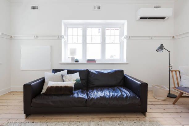 A Living Room With a Black Leather Couch and a Window — Enterprise Air That's Cool in Bullyard, QLD