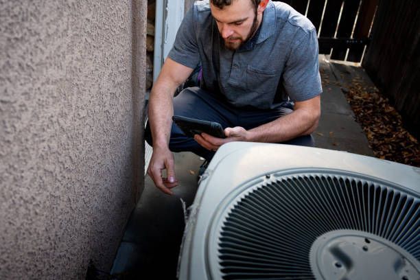A Man is Kneeling Down Next to an Air Conditioner — Enterprise Air That's Cool in South Bingera, QLD