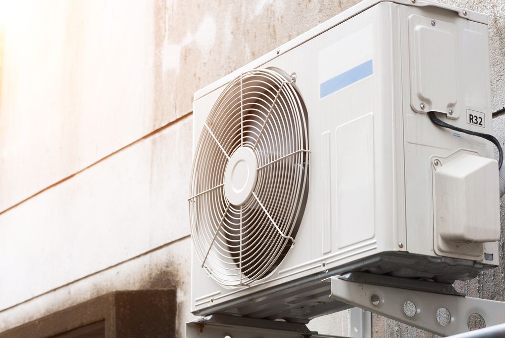 A White Air Conditioner is Mounted on the Side of a Building — Enterprise Air That's Cool in South Kolan, QLD
