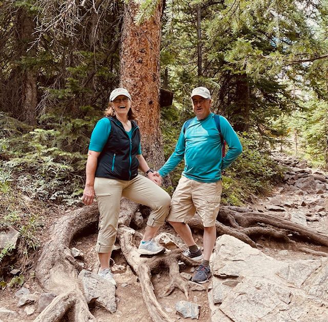 A man and a woman are standing next to each other in the woods.