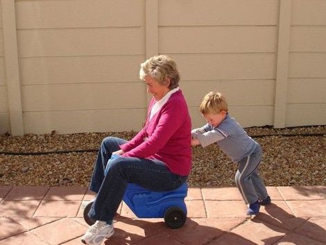 A little boy is pulling a woman on a blue toy