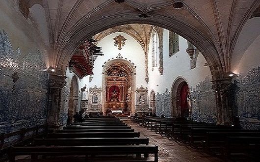 The inside of a church Holy Cross with blue and white tiles and rows of benches.