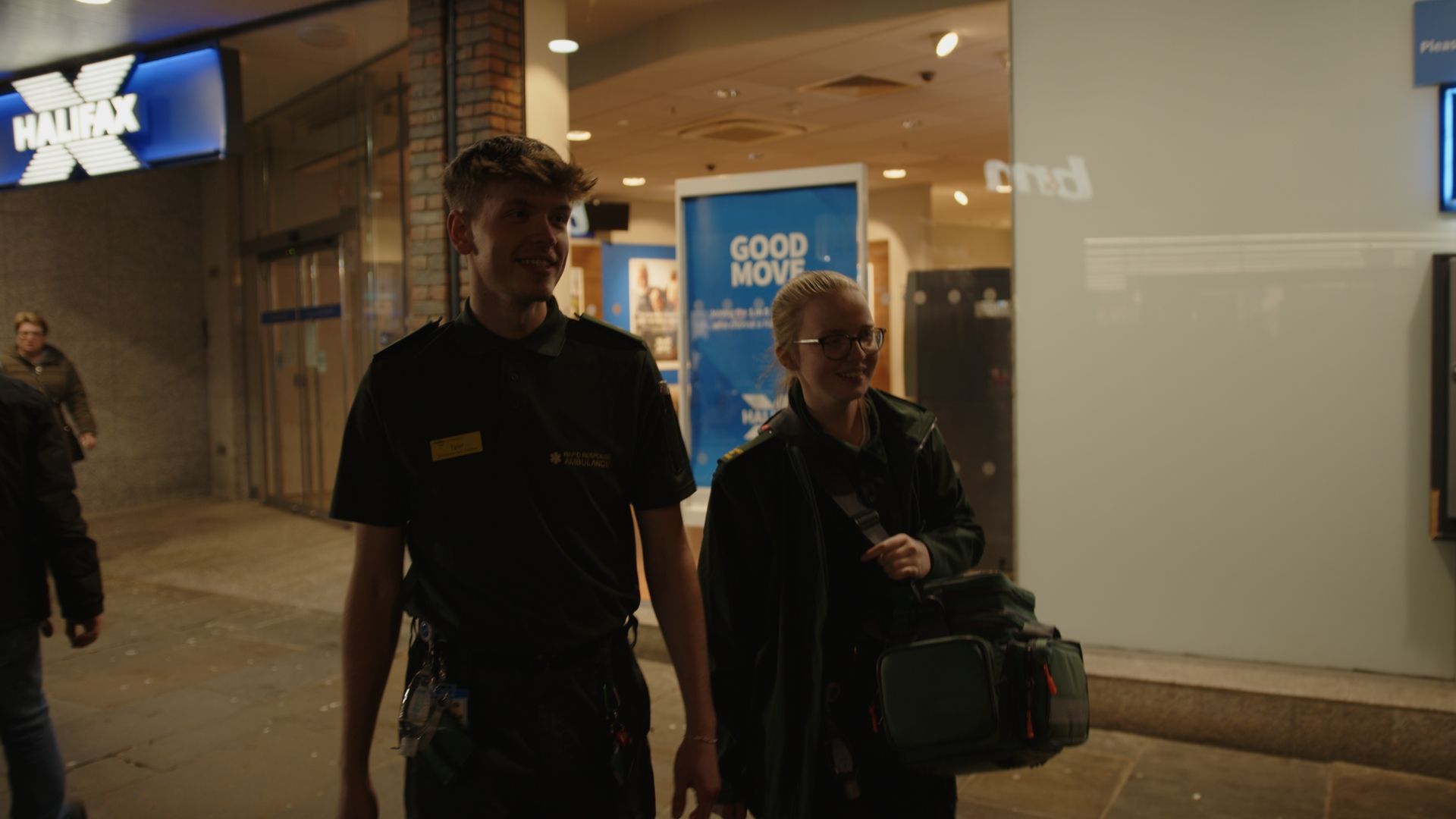 Two police officers are walking with a woman in a shopping mall.
