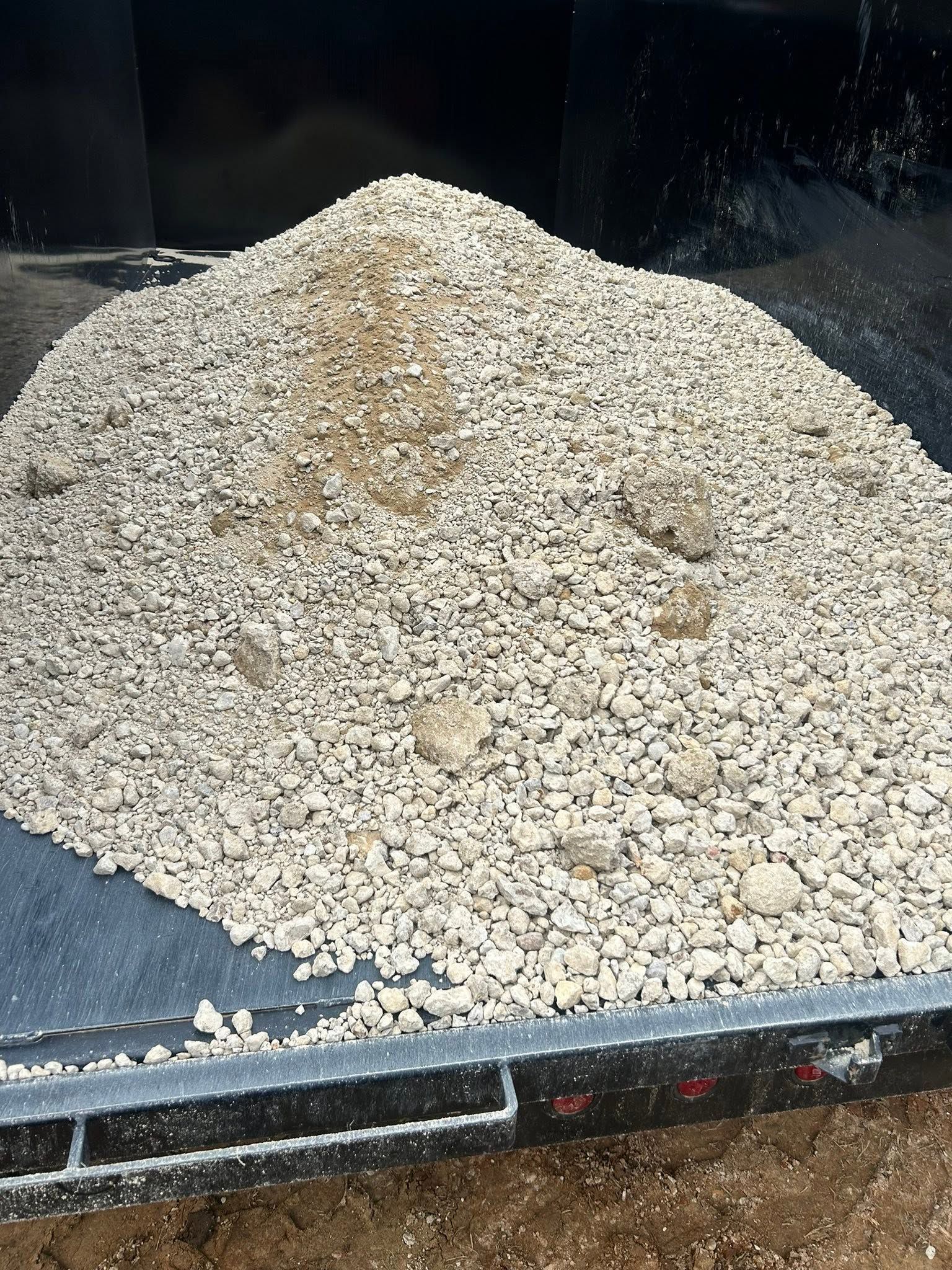 Pile of light-colored gravel in a black dump truck bed