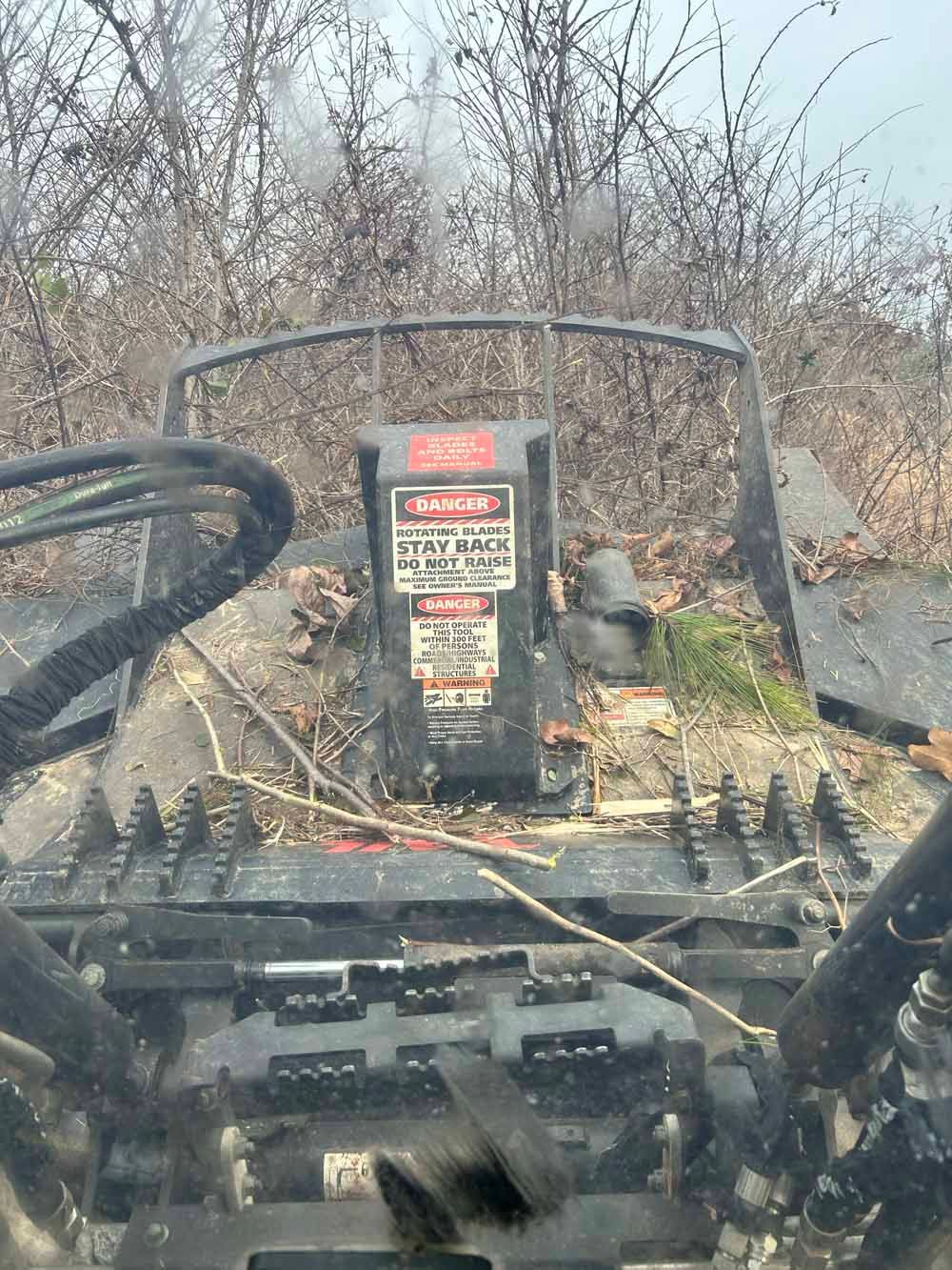 View from a rugged vehicle dashboard through brush, with a warning sign centered ahead.