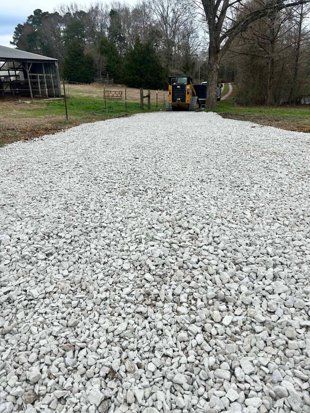 Freshly laid white gravel path with a small machine at the far end in a rural yard