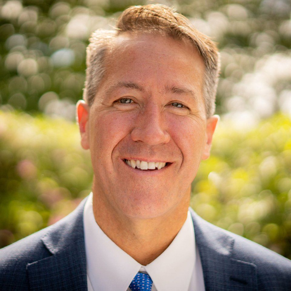 A man with a beard is wearing a blue suit and a blue shirt.