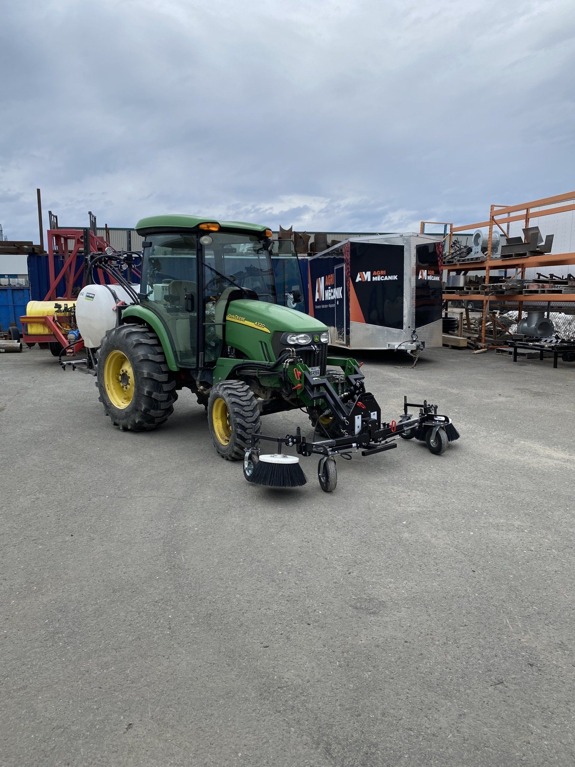 Un tracteur vert est garé dans un parking à côté d une remorque.