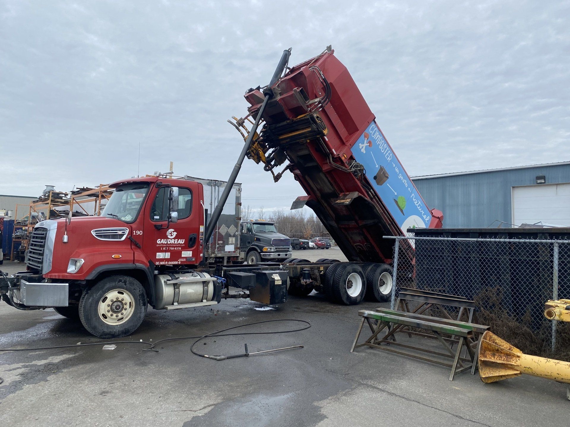 Un camion-benne rouge est garé dans un parking.