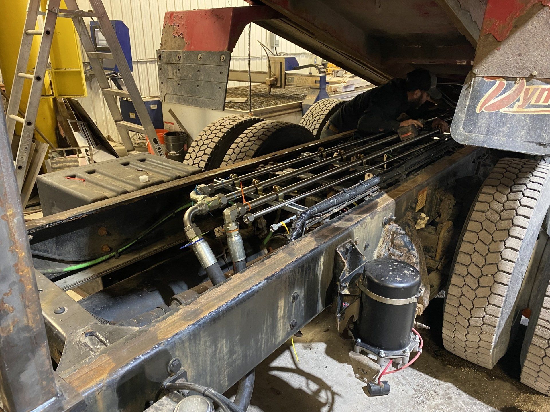 Un camion auquel sont fixés des flexibles hydrauliques se trouve dans un garage.