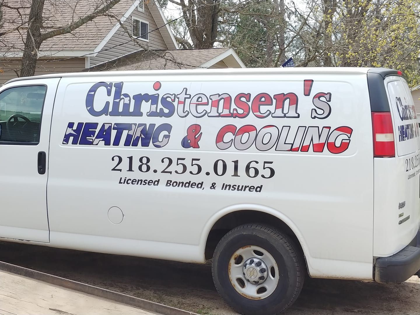 A christensen 's heating and cooling van is parked in front of a house