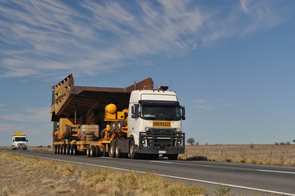 A White Truck With A Yellow Sign On The Front That Says Oversize — Castledine's Truck Painting & Repairs in Lake Macquarie, NSW