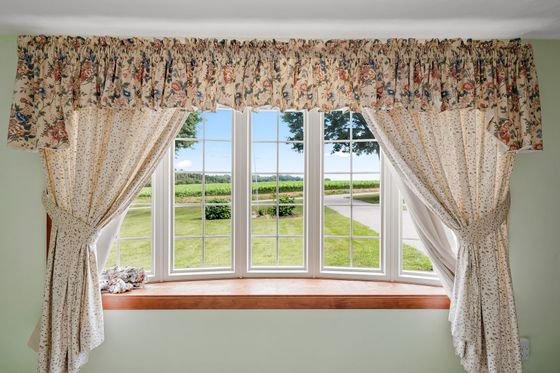 2014 Peterman Rd Property - floral curtains framing a bay window with a view of green fields and a driveway outside
