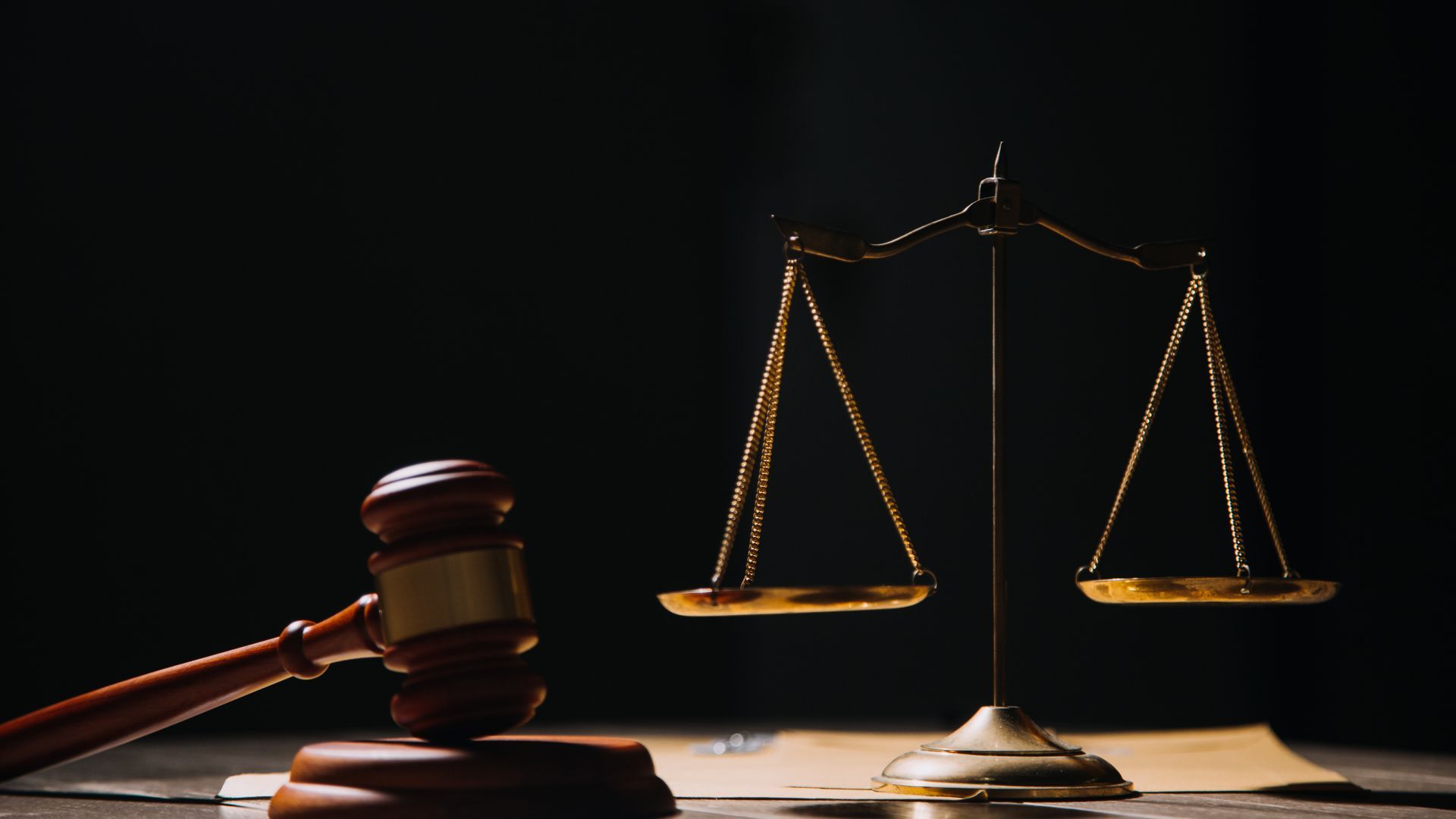 A judge 's gavel and scales of justice are on a wooden table.