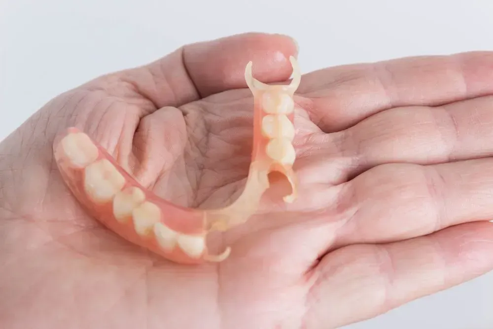 A Person is Holding a Denture in Their Hand — Twin Towns Denture Clinic In Forster, NSW
