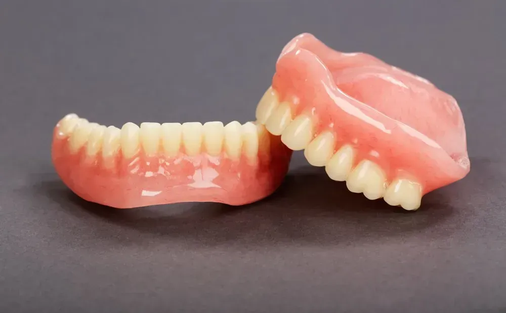 A Pair of Dentures Are Sitting on Top of Each Other on a Table — Twin Towns Denture Clinic In Forster, NSW