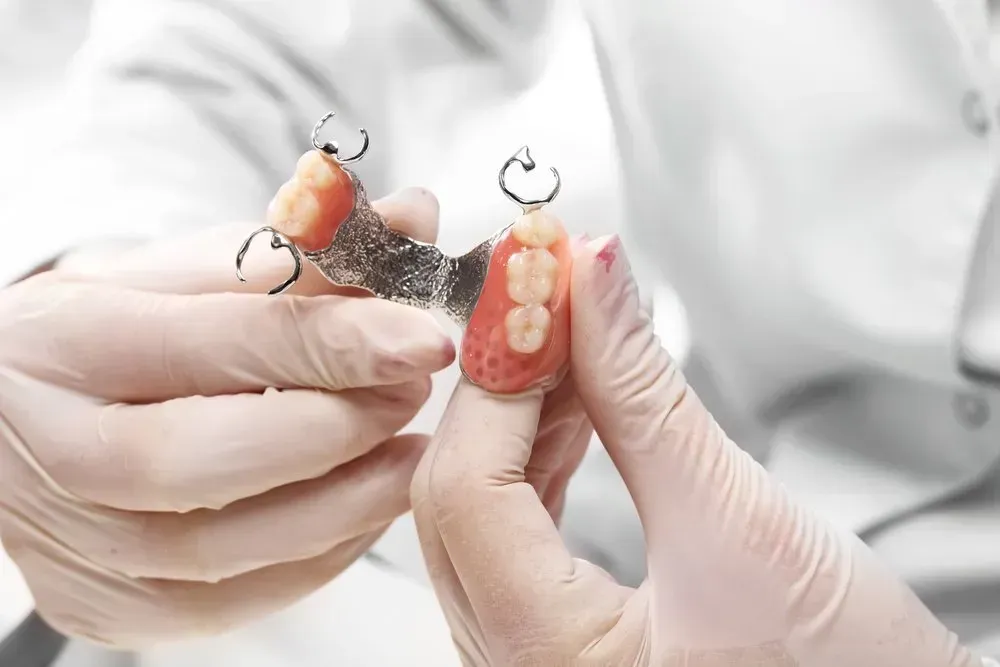 A Dentist is Holding a Denture in His Hands — Twin Towns Denture Clinic In Forster, NSW