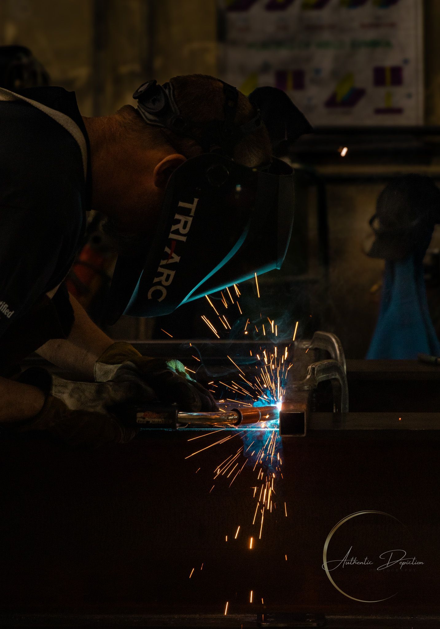 Man inspecting long metal structure on wheels inside a workshop, another person in background.