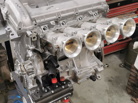 The hood of a red car is open and shows the engine. The hood of a red car is open and shows the engine.