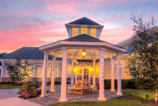 The front door of a house with a porch and plants in front of it.