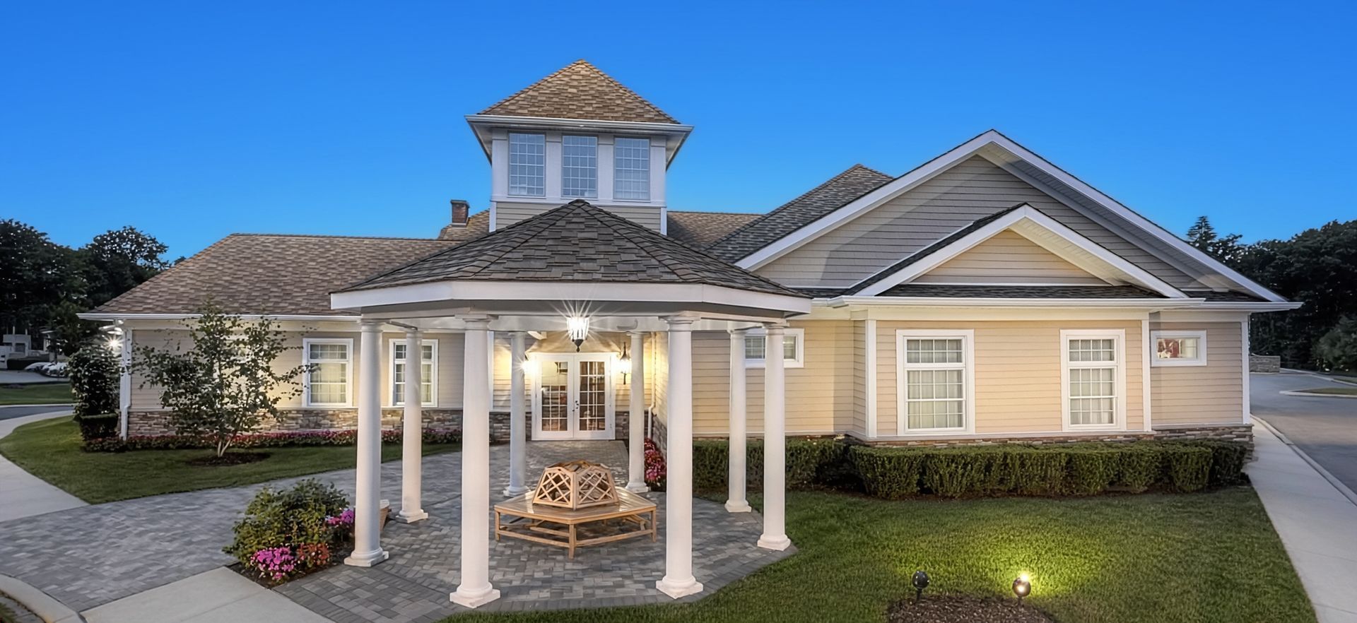 Single-story beige house with a front porch and white columns at dusk
