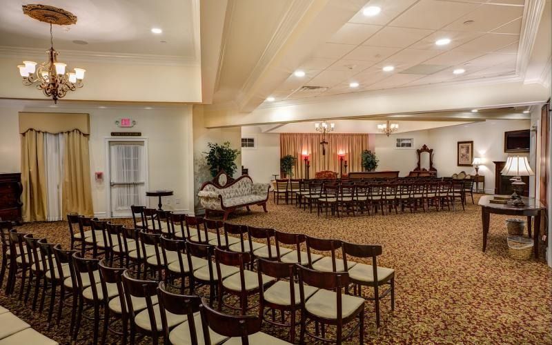 Empty banquet hall with rows of chairs facing a decorated stage and dining tables
