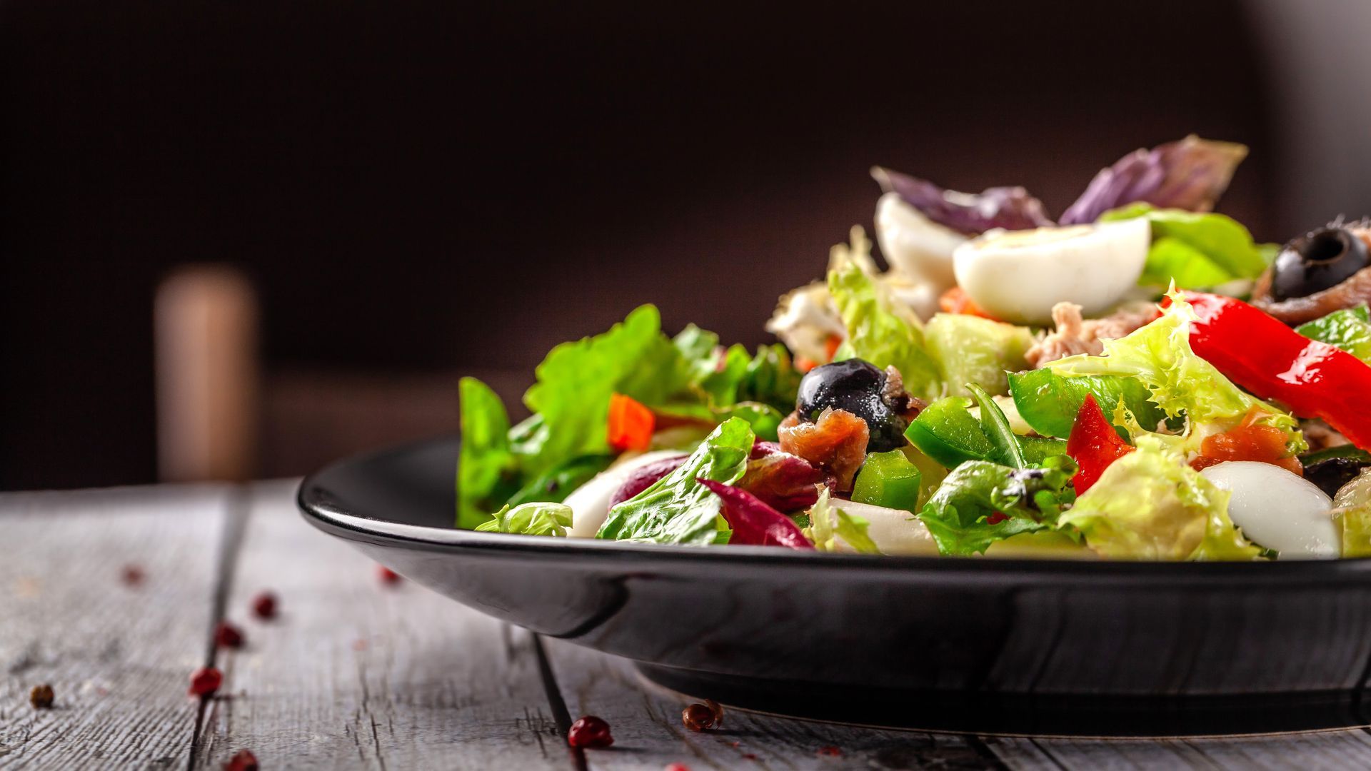 A close up of a salad on a plate on a wooden table.