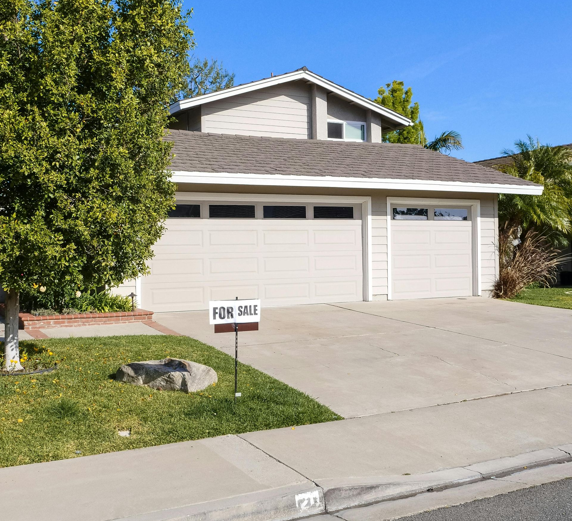 Suburban house with a “For Sale” sign in the front yard and a two-car garage. Homes for sale in Springfield