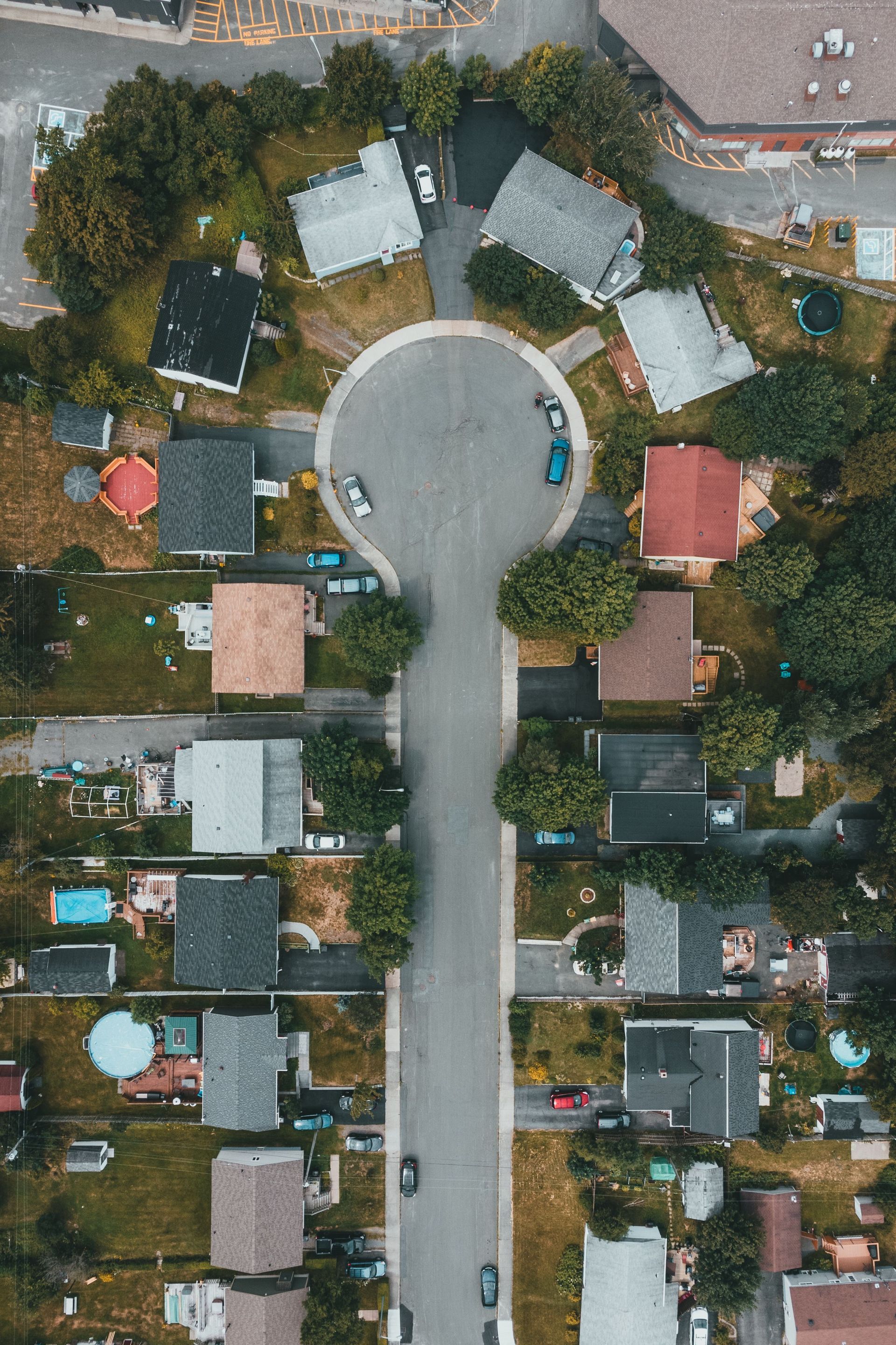 Aerial view of a quiet cul-de-sac with houses, driveways, trees, and parked cars. | Family friendly realtor Springfield MO