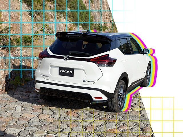 Un SUV compacto blanco estacionado en una calle empedrada junto a un muro de piedra y una valla azul.