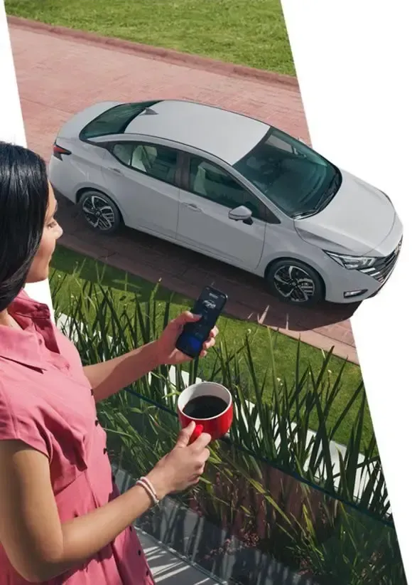 Persona con una bebida y un control remoto observa un automóvil plateado estacionado junto a la acera.
