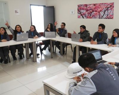 Personas en una reunión alrededor de una mesa con computadoras portátiles.