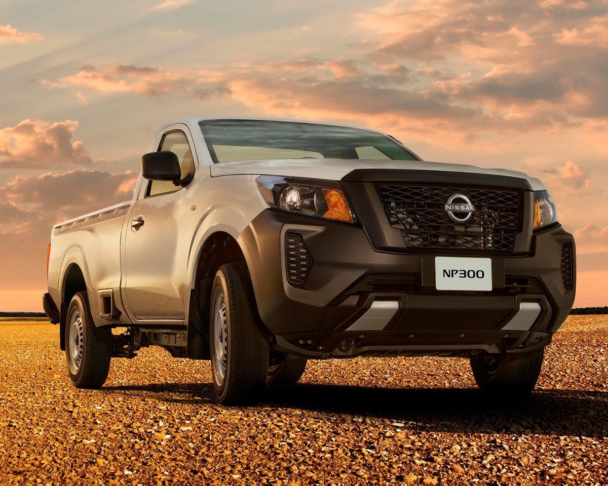 Camioneta Nissan blanca estacionada sobre grava al atardecer bajo un cielo colorido