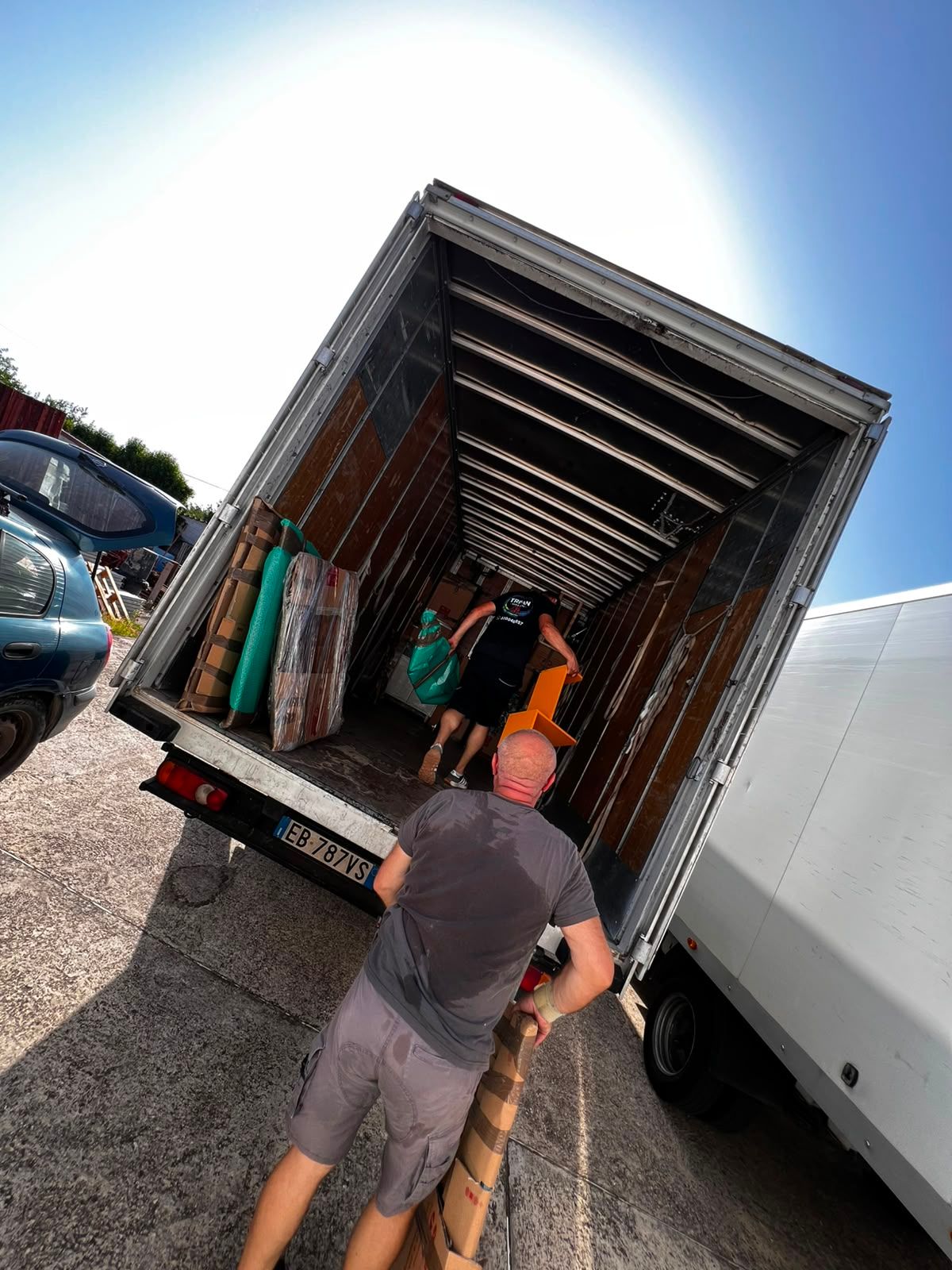 Alcune persone caricano appendiabiti su un camion per traslochi scoperto in un parcheggio.
