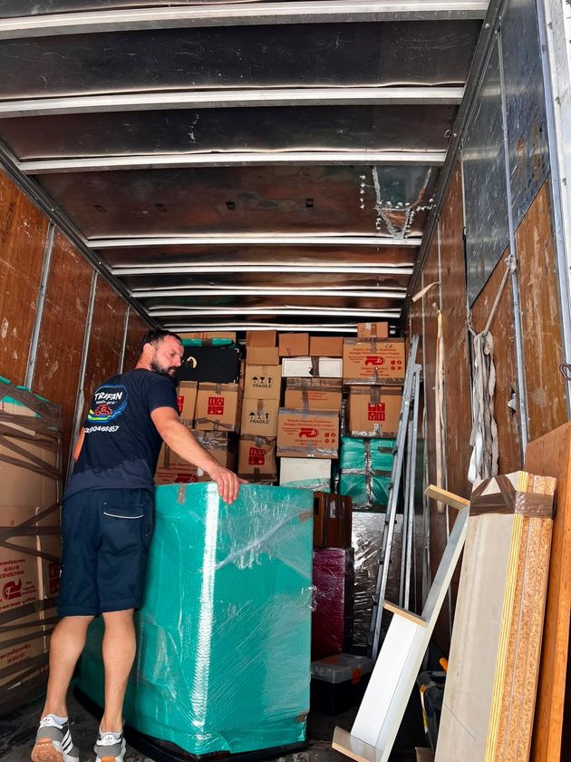 Due persone caricano scatole di cartone su un camion, una delle quali utilizza un carrello.