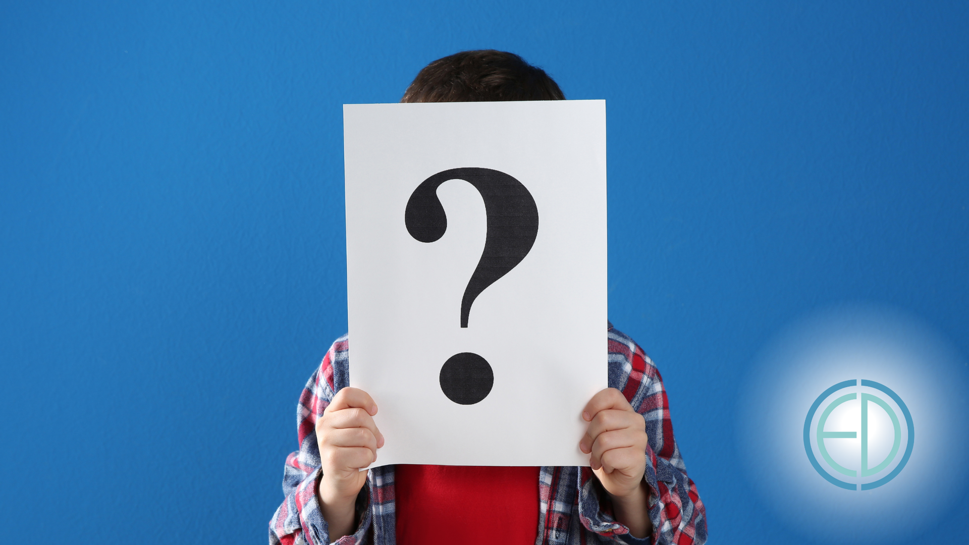 Person holding a white sign with a black question mark in front of their face, against a blue background.