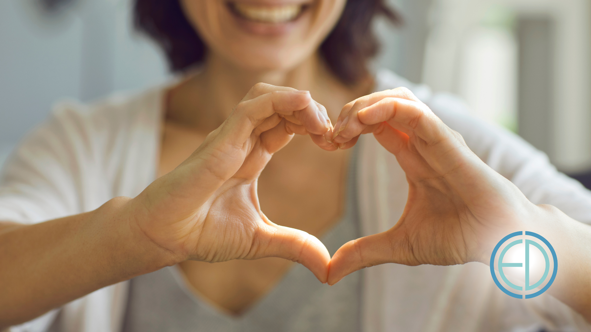 A woman is making a heart shape with her hands.