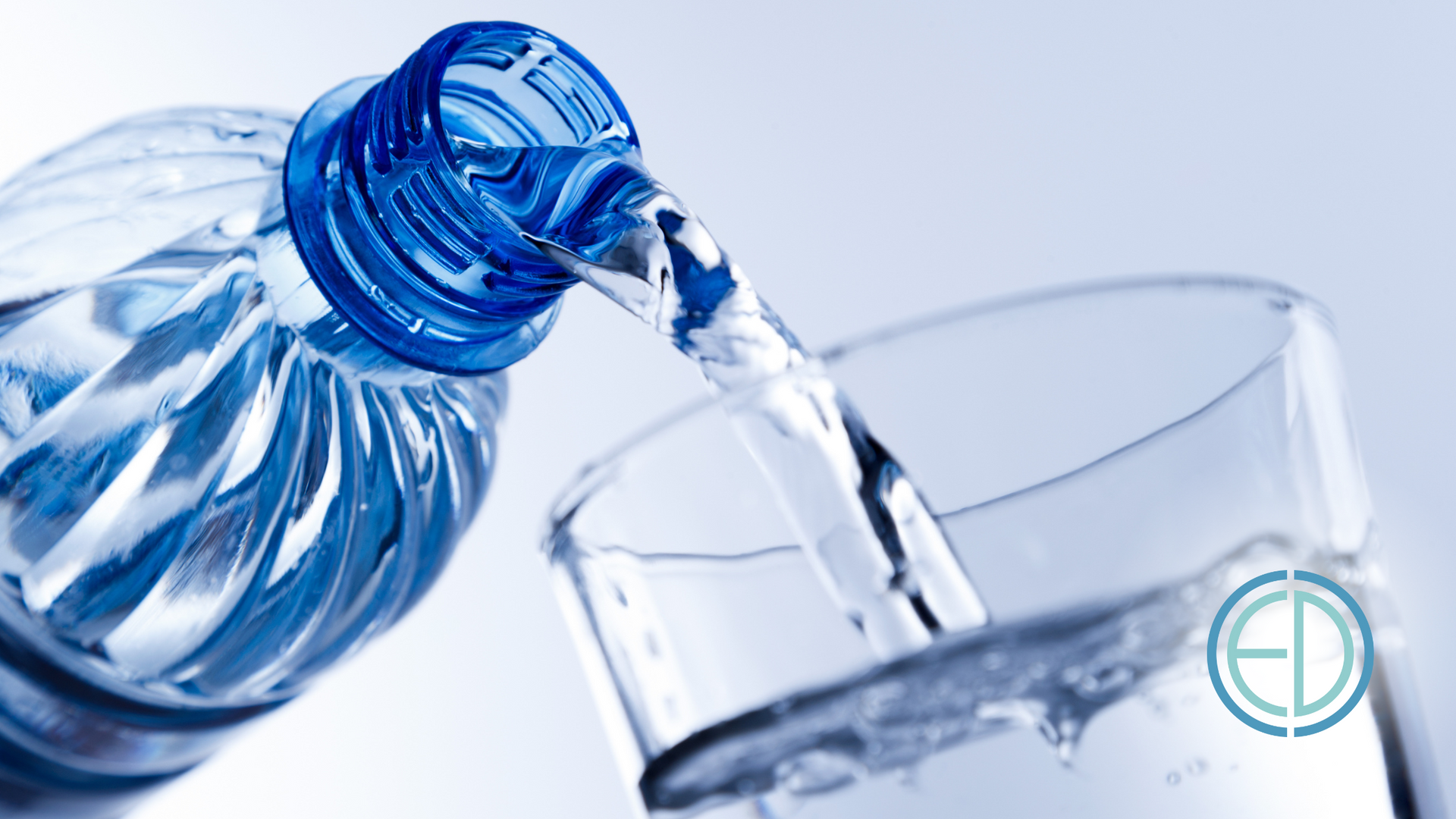 Bottle pouring water into a glass; blue bottle and cap, clear water, light background.