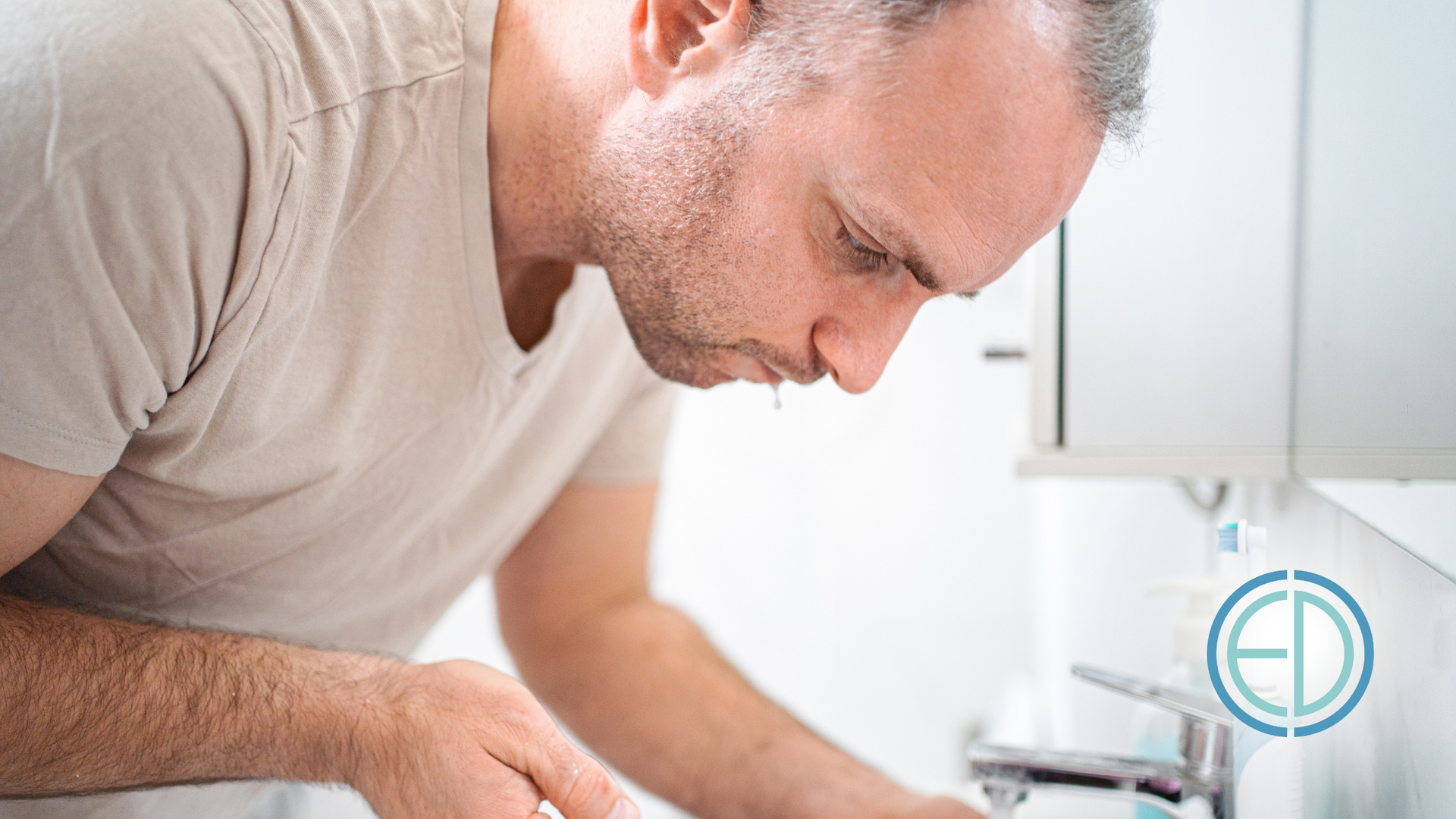 A man is brushing his teeth in a bathroom sink.