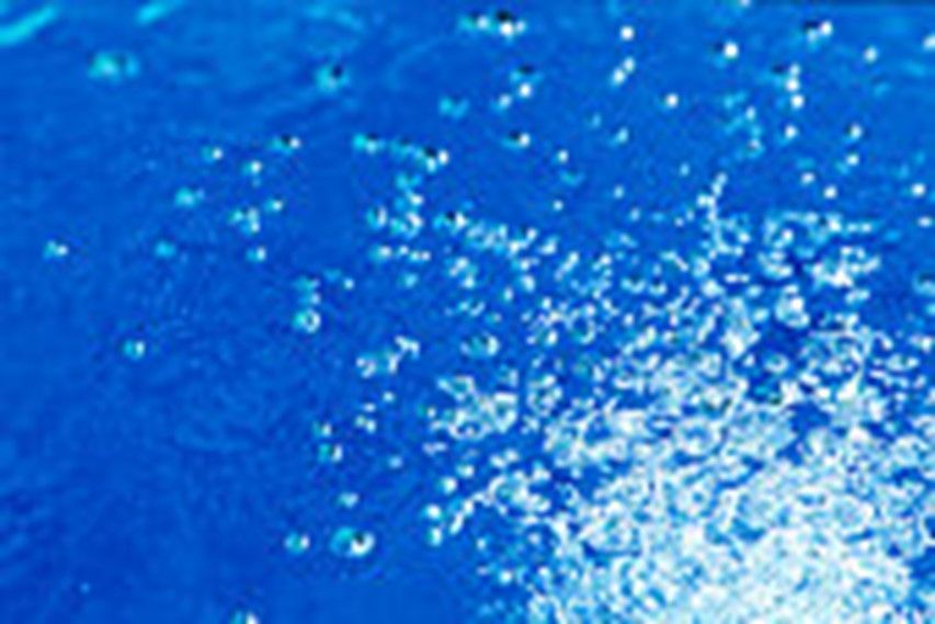 Water Softening Treatment with air bubbles symbolizing purity and clarity | Carroll County, AR Close-up of bright blue water with dynamic white splashes and bubbles on the surface.