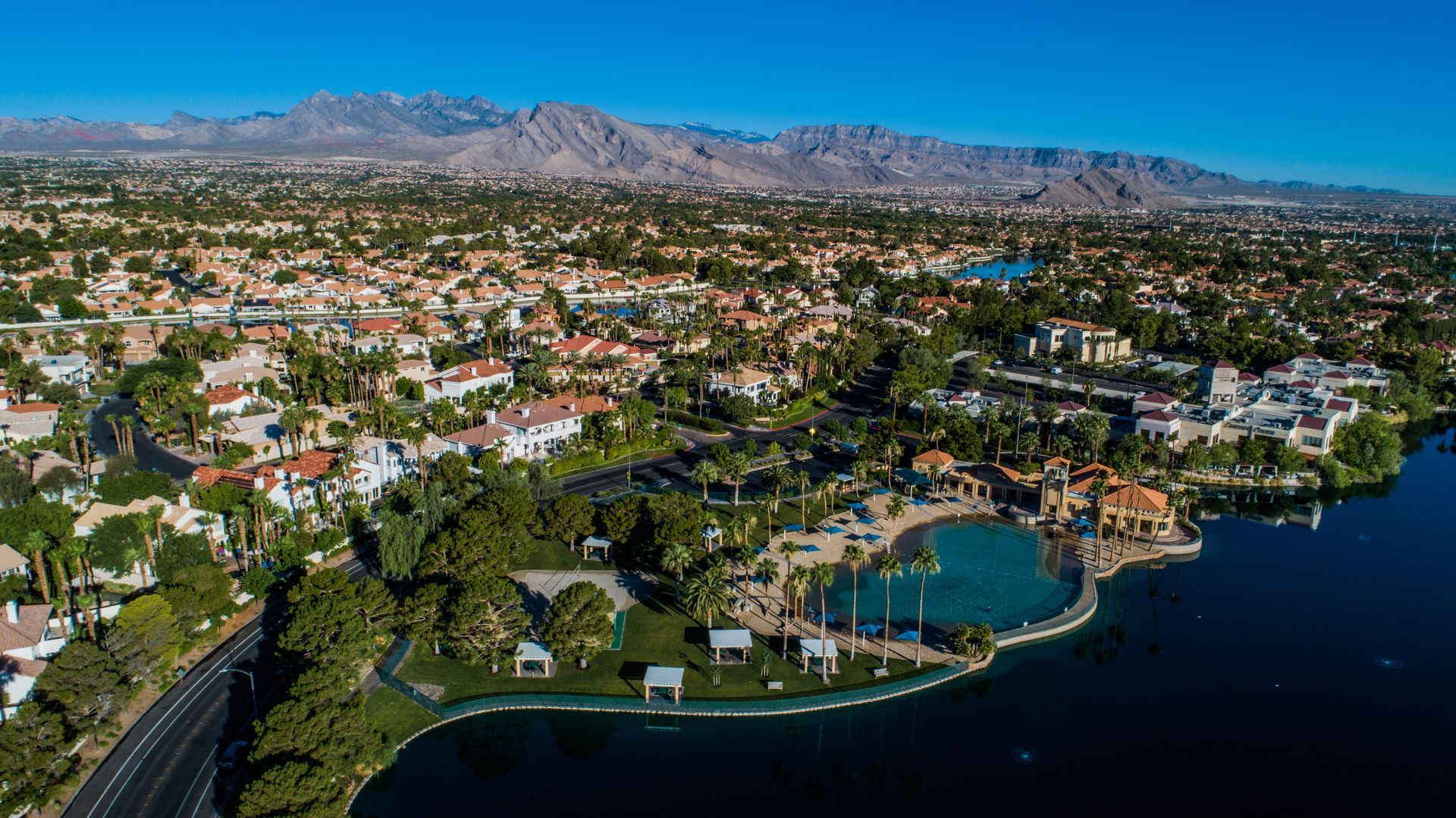 Aerial view of a lakeside suburban neighborhood with palm trees — Las Vegas real estate photography