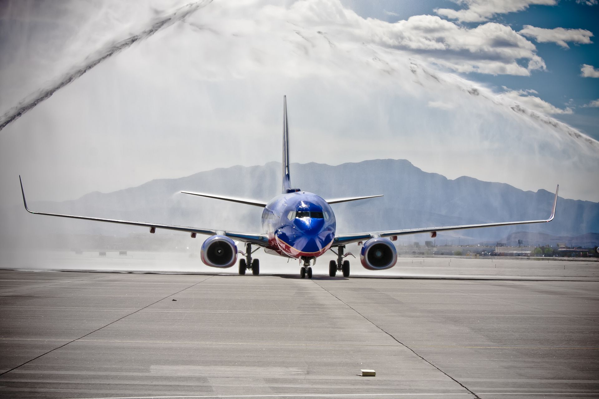Blue airplane taxiing on a runway with mountains and mist in — Las Vegas multi-family photography