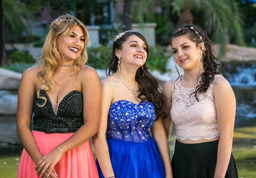 Three smiling women in formal dresses standing outdoors at an event — portrait photography
