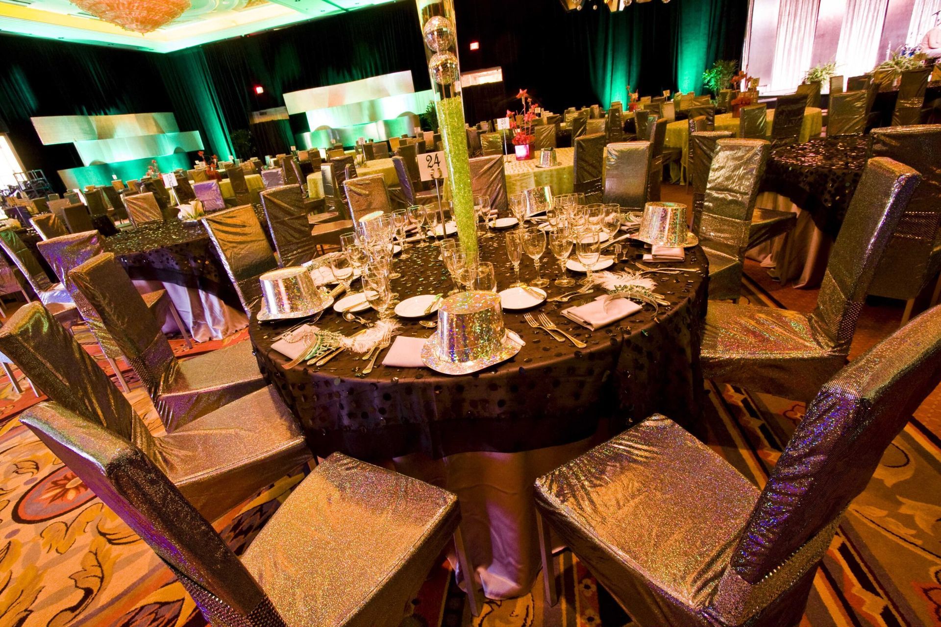 Round banquet tables set with plates and glasses in a warmly lit event — advertising photography