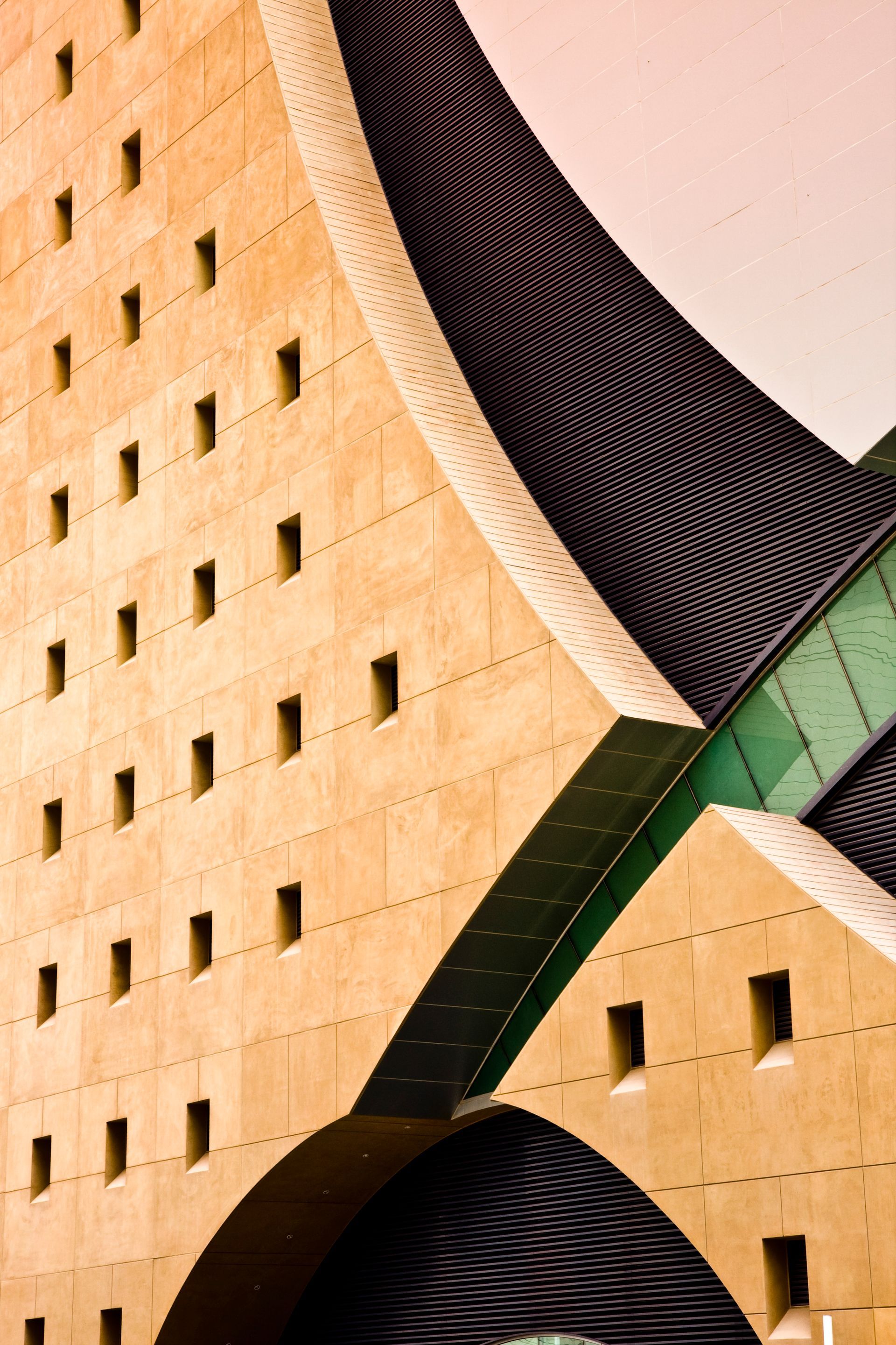 Abstract modern building facade with tan panels, black arches, and a green diagonal structural beam — Las Vegas architectural photography