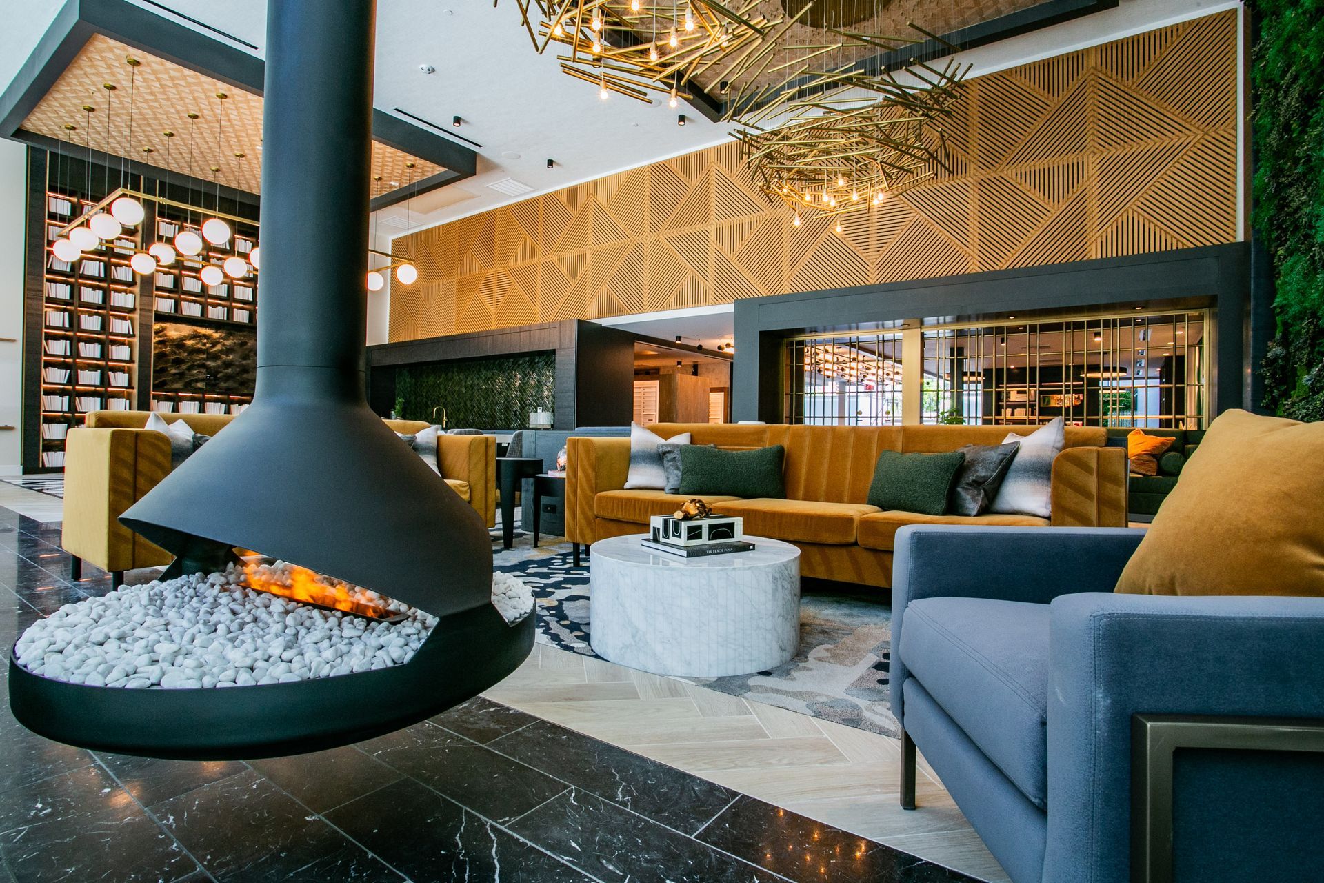 Modern hotel lounge with a suspended fireplace, blue and gold seating, and warm wood accents — Las Vegas commercial multi-family property photography