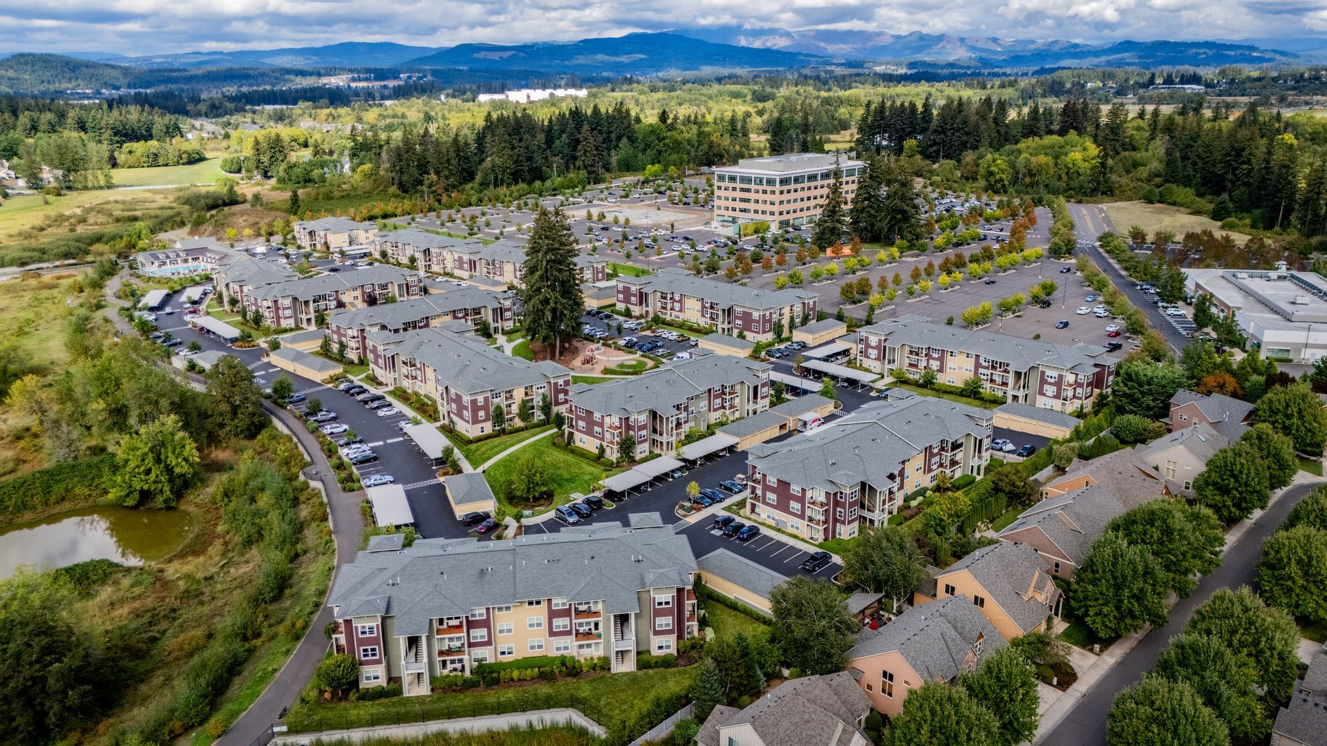 Aerial view of a large apartment complex with parking lots, trees — multi-family photography
