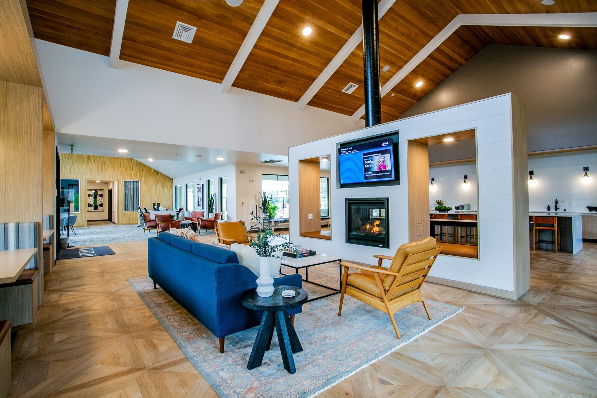 Open-concept living room with blue sofa, wicker chairs, fireplace — multi-family photography