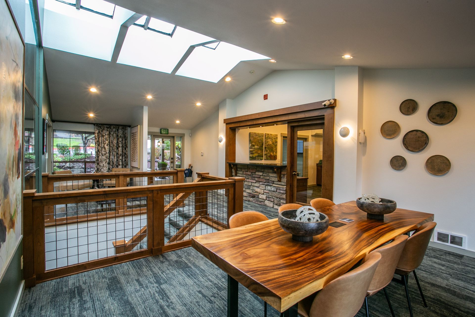 Modern open dining area with wooden table, railing, skylights, and wall decor in a bright interior — commercial multi-family property photography